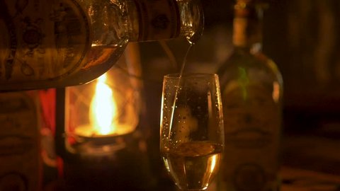 Close up of a person pouring tequila in a champagne flute lit by lantern in a dark tasting room