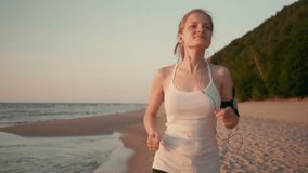 Young Slender Woman Runner is Jogging on the Beach at Sunset or Sunrise at Sea Coast. Beautiful SlowMotion 4K video Footage.