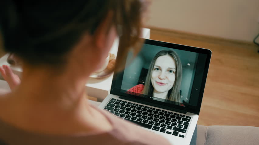 Adult Woman is Making Video Call to talk via Internet and Greeting her Interlocutor by Waving Hand via Webcam in Laptop | Shutterstock HD Video #1012582784