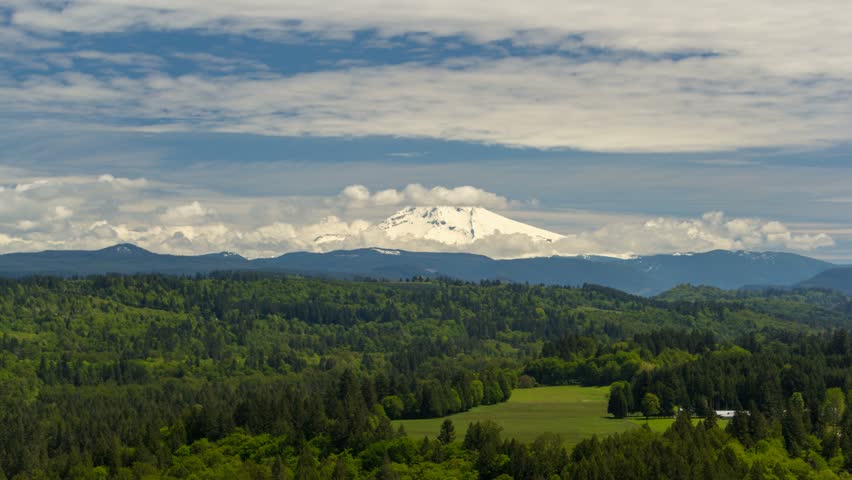 Ultra high definition 4k timelapse movie of moving white clouds and blue sky over majestic snow covered Mt. Hood and Sandy river valley in Portland Oregon spring season 4096x2304