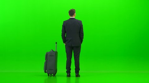 businessman walking with a suitcase on green background 