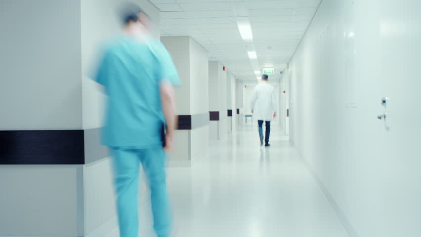 Time-Lapse of the Busy Hospital Corridor: Doctors, Nurses, Surgeons and Patients Walk through the Hallway of this Modern and Bright Clinic. Shot on RED EPIC-W 8K Helium Cinema Camera.