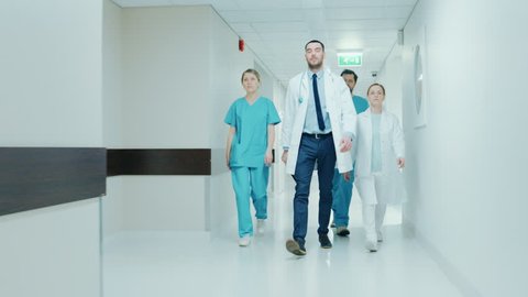 Team of Doctors, Surgeons and Nurses Walk Through Busy Hospital Hallway, They Talk about Patients, Forthcoming Surgeries and Saving Lives. Shot on RED EPIC-W 8K Helium Cinema Camera. स्टॉक वीडियो