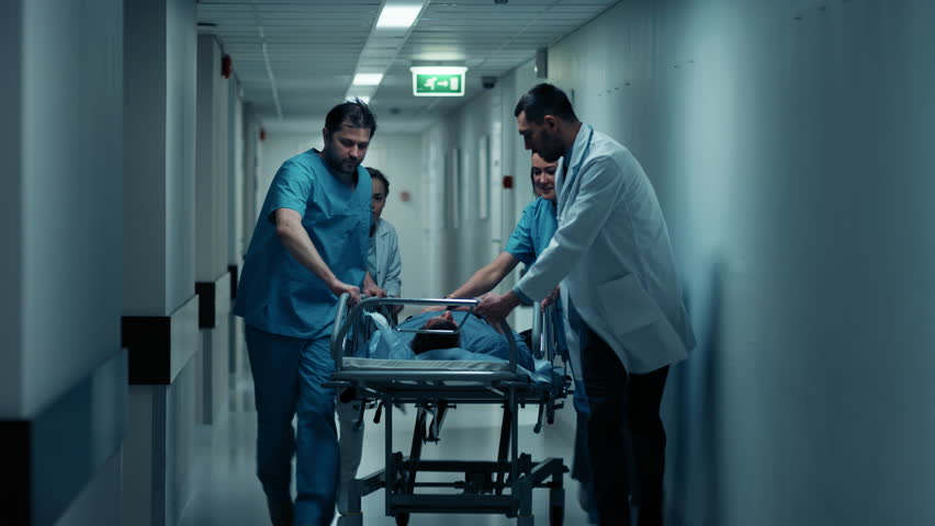 Emergency Department: Doctors, Nurses and Paramedics Run and Push Gurney / Stretcher with Seriously Injured Patient towards the Operating Room. Shot on RED EPIC-W 8K Helium Cinema Camera.