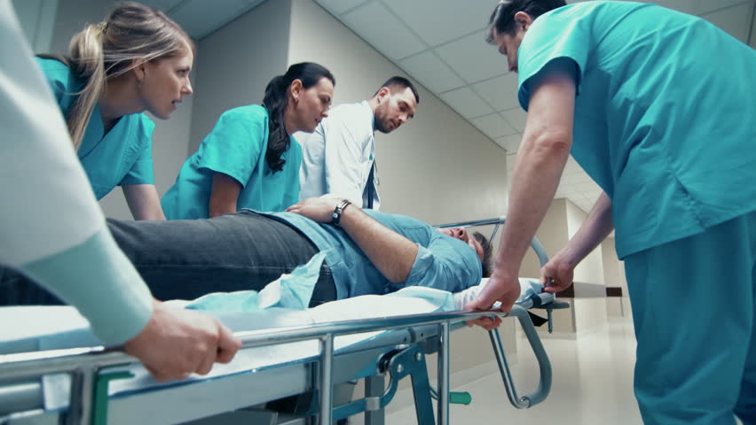 Emergency Department: Doctors, Nurses and Paramedics Run and Push Gurney Stretcher with Seriously Injured Patient towards the Operating Room.  Shot on UHD 4K Camera. Royalty-Free Stock Footage #1012593878