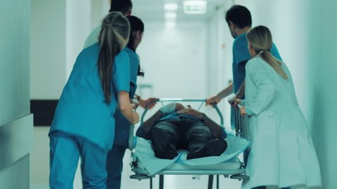Emergency Department: Doctors, Nurses and Paramedics Push Gurney / Stretcher with Seriously Injured Patient towards the Operating Room. Bright Modern Hospital with Professional Staff Saving Lives. 4K.