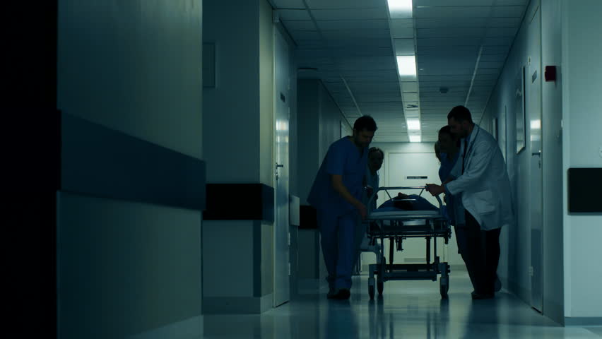 Emergency Department: Doctors, Nurses and Paramedics Push Gurney  Stretcher with Seriously Injured Patient towards the Operating Room. Shot on RED EPIC-W 8K Helium Cinema Camera. Royalty-Free Stock Footage #1012593887