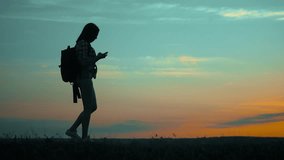 silhouette hiker girl traveler with smartphone navigation search ways. the girl nature search position navigation slow motion lifestyle video silhouette girl travel concept woman