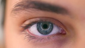 Beautiful human eye close-up. Young Woman Blue one eye macro shoot. Macro Closeup eye blinking and looking up. 4K UHD video