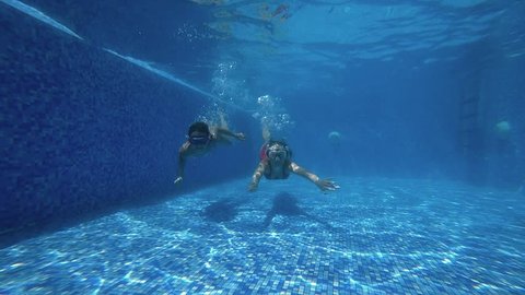 Two happy active girls in the swimming pool, underwater view. Slow motion 120 FPS. Underwater shooting.