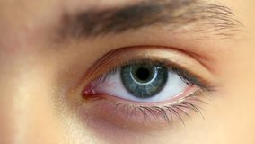 Beautiful human eye close-up. Young Woman Blue one eye macro shoot. Macro Closeup eye blinking and looking up. 4K UHD video