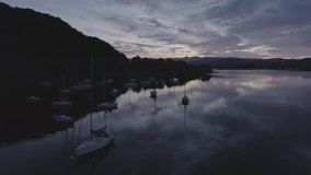 Lake at sunrise with moored yachts reflections of clouds 