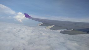 Scenery from the flight. Top View of Blue Sky with White Mostly Cloudy from the Plane in the Air, the Wing of passenger airplane - the view through the window.Travel on vacation. Mobile Phone Video.