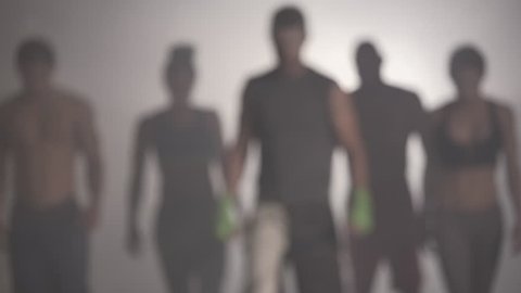 Shadowy Athletes walking towards camera in slow motion in the fog