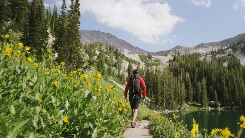 Tracking shot of man hiking next to mountain lake in Little Cottonwood Canyon, Utah
