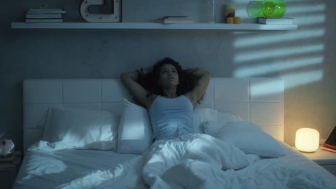 Young hispanic woman sleeping in bed at home. Restless sleep for black girl in bedroom. People suffering with anxiety disorder and having health problems