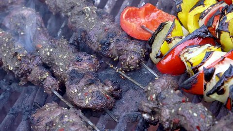 Closeup of shish kabobs with meat and peppers and onions grilling on a hot barbecue.