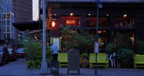 A nighttime summer establishing shot of a typical corner Manhattan bar or restaurant entrance.  