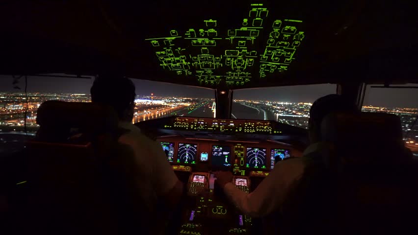 Two pilot were operating the airplane in landing phase. Airplane was touching down on the runway in airport at night, able to see beautiful view of cityscape and lights of runway from inside cockpit. Royalty-Free Stock Footage #1012630166