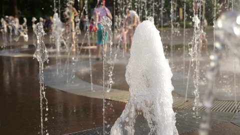 Children play in a stream of water City fountain. Summer South. 4k, slow motion, blur