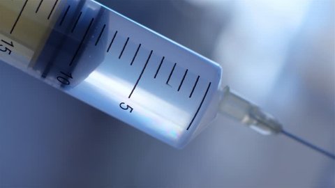 The syringe slowly injects the solution. A very close-up view of the syringe plunger. Drawing of liquid in a syringe. 