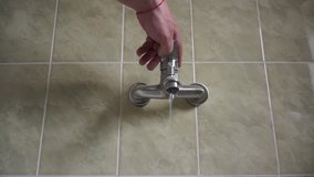man's hand opens the tap with water in the bathroom and closes the water. At home.