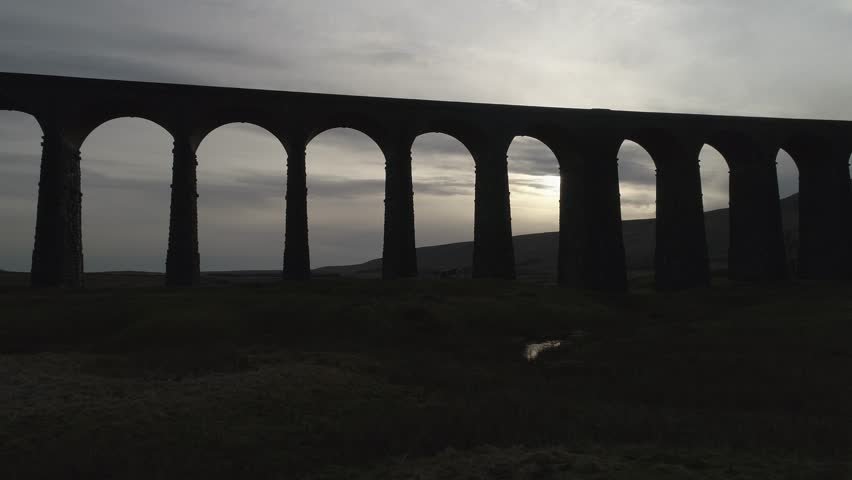 Viaduct - Fast moving left to right low shot with drone and sun showing through arches