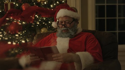 Santa reading in front of Christmas tree