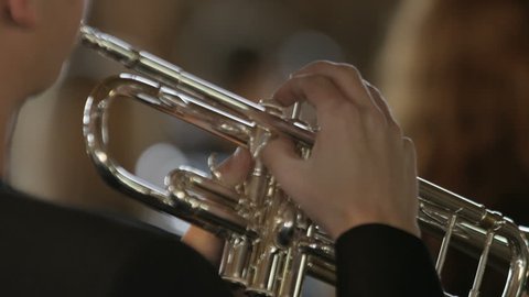 Close up of a boys hands playing trumpet, camera focuses onto girl with clarinet
