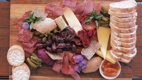 Flat lay of Cheese and Meat Platter With Hands Reaching in to take food