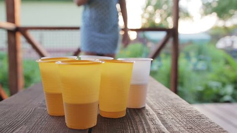Friends play in the beer pong terrace. The girl throws a ball in a glass, a man drinks a beer. Close up