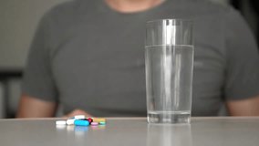 man taking pills at home is ill sick slow motion video. Healthcare and medical concept disease. male takes a pill and drinks a glass of water indoors lifestyle