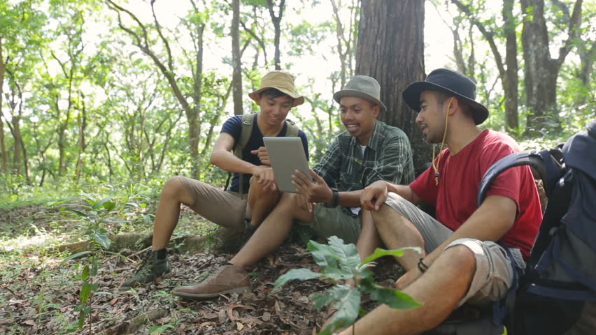 three people using tablet pc together in the forest