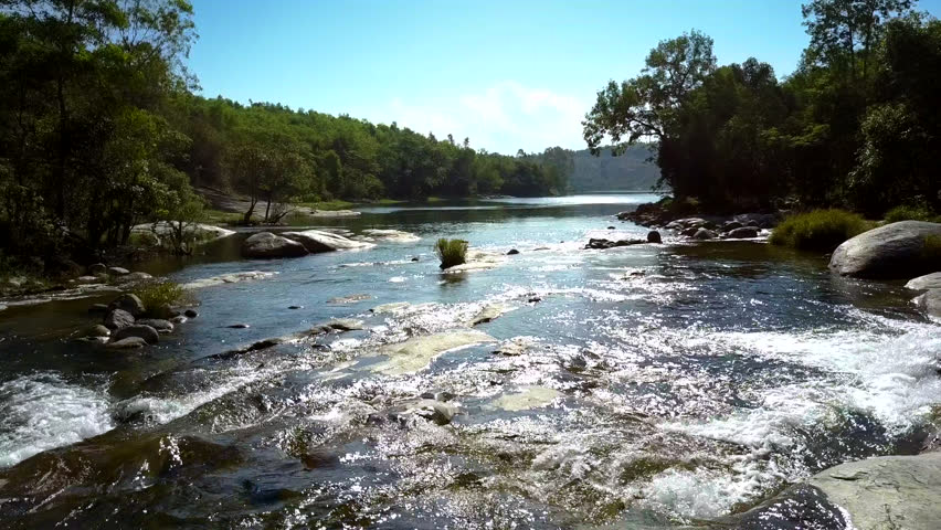 Drone view pictorial river streams and shimmers under scorching sun rays against jungle landscape