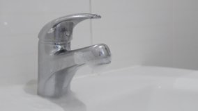 Slow motion of sprayed bathroom faucet against limescale