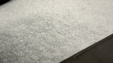 Plastic granules in container of the extrusion equipment. Shot in slow motion