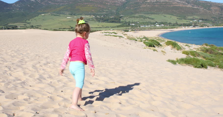 funny scene: four years old blonde happy girl trying to do the somersault or handstand on sand dune, in Valdevaqueros Beach, Tarifa, Cadiz, Andalusia, Spain, Europe
