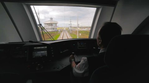 KAZAN, TATARSTAN/RUSSIA - MAY 14 2018: Professional man driver drives powerful electrical train past railway station among wide fields on May 10 in Kazan