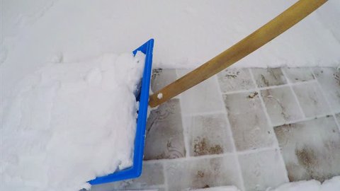 Removing snow with snow shovel from the sidewalk after snowstorm.