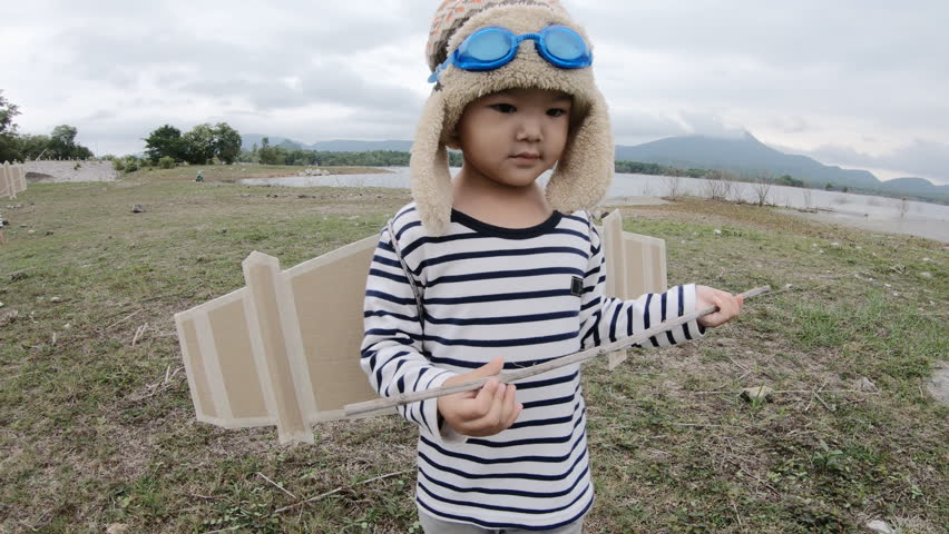 Happy child playing with toy wings against summer 