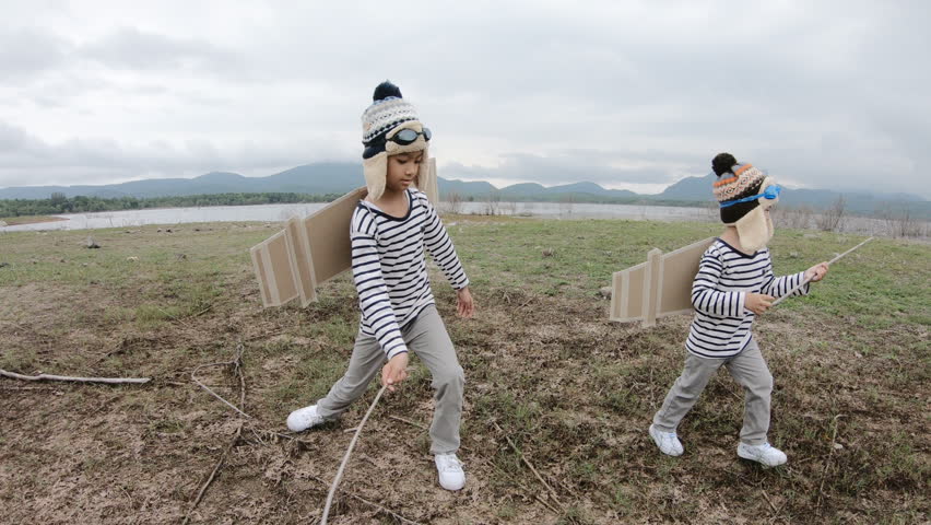 Happy child playing with toy wings against summer 