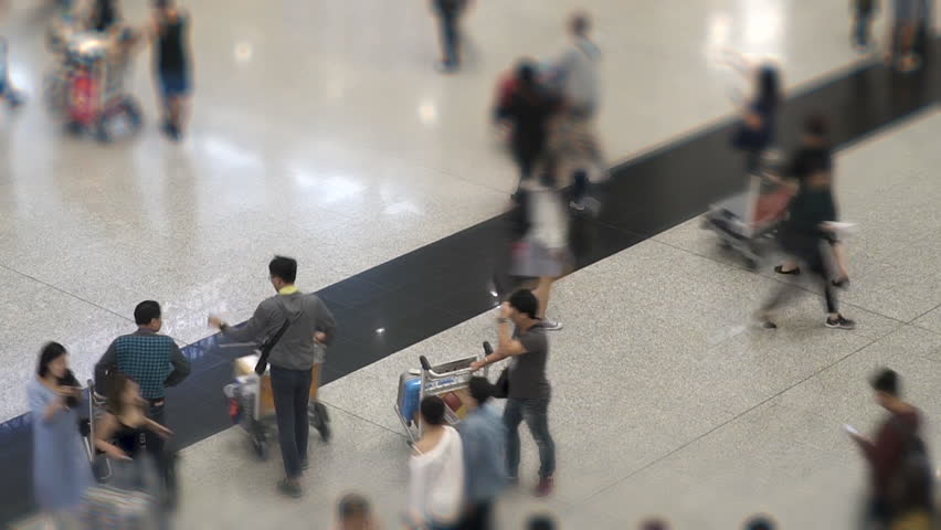 Time lapse of crowd of unrecognizable people walking with luggage in the international airport. Travellers tourists in Hong Kong Airport Terminal