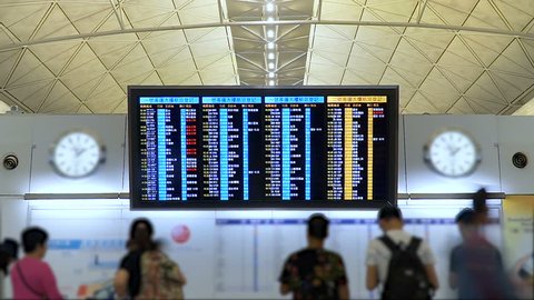 Time lapse. People in international airport looking at the flight information board, checking their flights. Tourists at international airport terminal flight timetable. Travel concept.