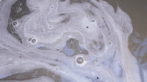 Dirty water with liquid sewage and foam, closeup