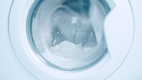 Washing machine washes white clothing and sheets. Cylinder spinning. Nobody. Blue tone