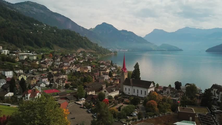 Lake Lucerne Switzerland aerial view. Flying above Weggis village on Swiss alps lake in the fall. Drone footage of picturesque hilltop village and countryside in autumn. Royalty-Free Stock Footage #1012690958