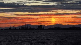 Beautiful Colors Tranquil Sunset Ocean Industrial Scene with cranes silhouettes 