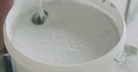 worker mixing water into gray decorative concrete plaster