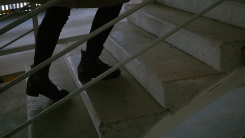 The girl climbs the old stairs, slow motion shooting. The girl climbs the stairs in the parking lot. Human feet climb the concrete staircase.