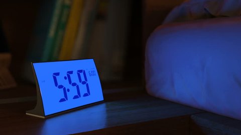 Digital alarm clock waking up at 6 AM. Close-up view. The numbers on the clock screen changes from 5:59 no 6:00 AM. Then alarm logo appears on the screen. 3D rendering animation.